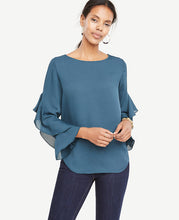Cascading ruffle sleeves add modern fluidity to this romantically refined top. Boatneck. Long ruffle sleeves. Shirttail hem. 25 long.