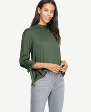 Ruched sleeve ties make our shirred mock neck distinctly feminine - and extra pretty. Shirred ruffle mock neck with back self ties. 3/4 sleeves with tunneled self ties. 23 3/4 long.