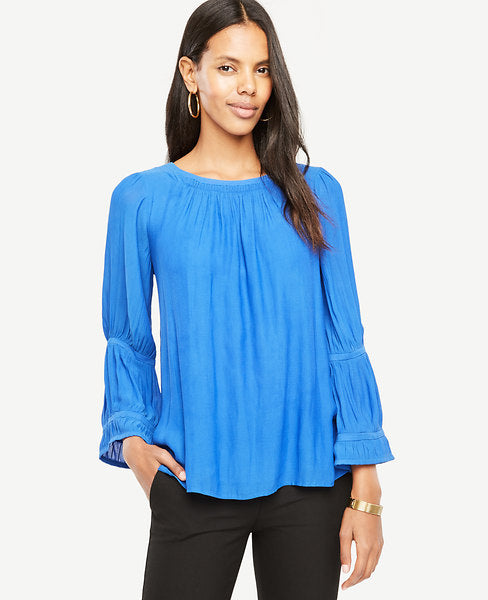 Flare sleeves accented with banded trim make a modern statement on our romantically shirred blouse. Shirred jewel neck. Long sleeves with shirred sleeve caps and sleeve insets. Back slit with button closure. 25 long.