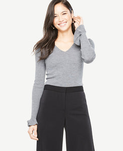 We gave this extrafine merino wool sweater a feminine twist with ruffled cuffs - and a flattering ribbed stitch. V-neck. Long sleeves with ruffle cuffs. 24 long.