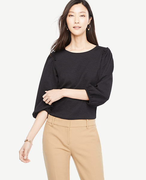 Our textured knit top turns up the volume with shirred puff sleeves and pretty shoulder ruffles. Jewel neck. 3/4 sleeves with shirred sleeve caps and cuffs. Shirred ruffle at shoulders. 23 1/4 from natural waist.